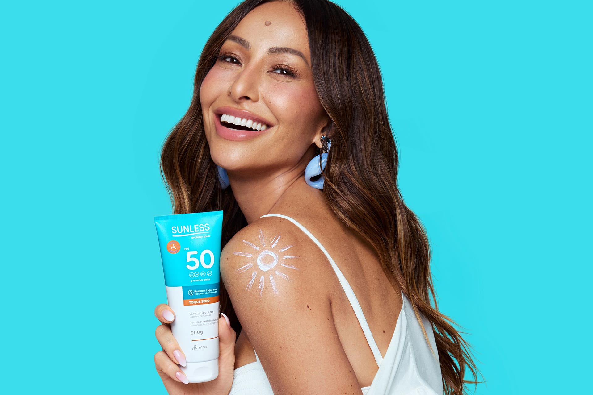 Sabrina Sato sorrindo segurando o produto Sunless